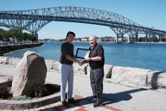 Clark Dunn (left) is awarded with the Tony Stranak Conservation Scholarship by St. Clair Region Conservation Authority Chair, Mike Stark (right) in front of the Bluewater Bridge in Sarnia.