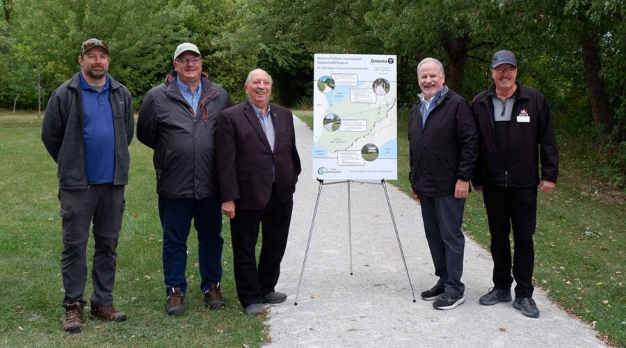 Five men standing on a trail beside a sign